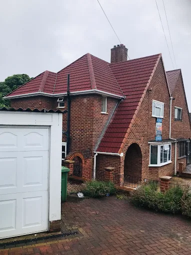 Red tiled pitched roof with brick chimney stack